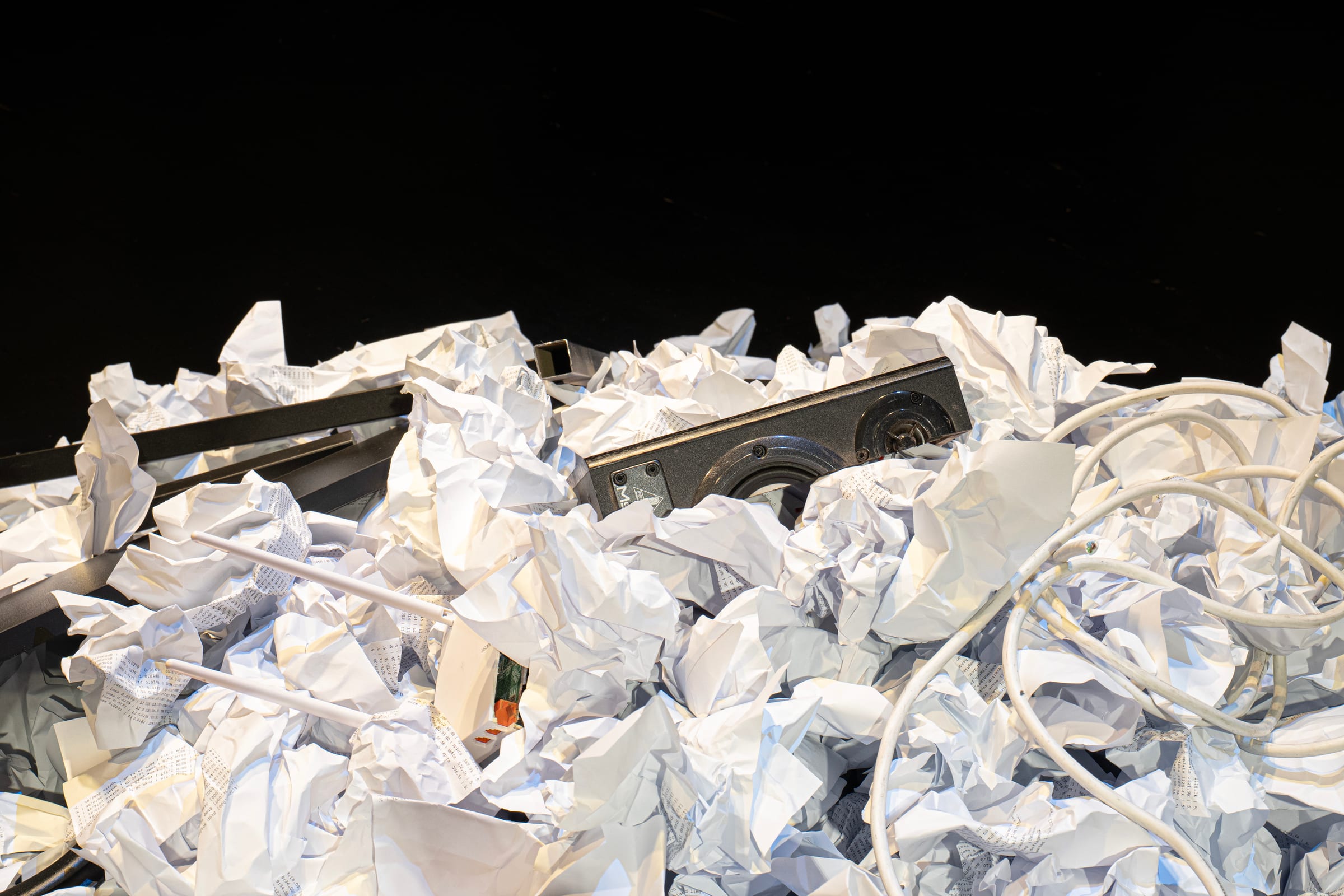 Speaker and cable buried in crumpled printouts