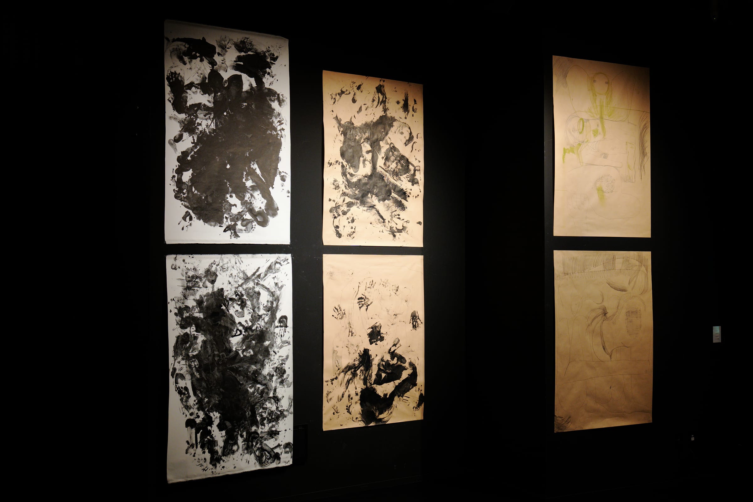 Works on paper lit against a dark wall
